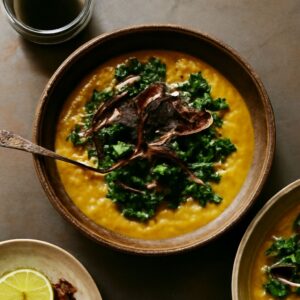 A bowl of collard green soup with a side of green habanero sauce